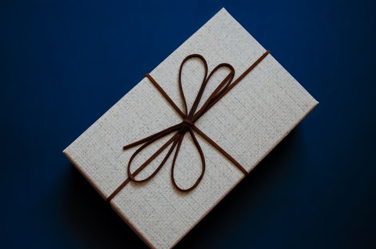 An elegant gift box with a brown ribbon on a deep blue background