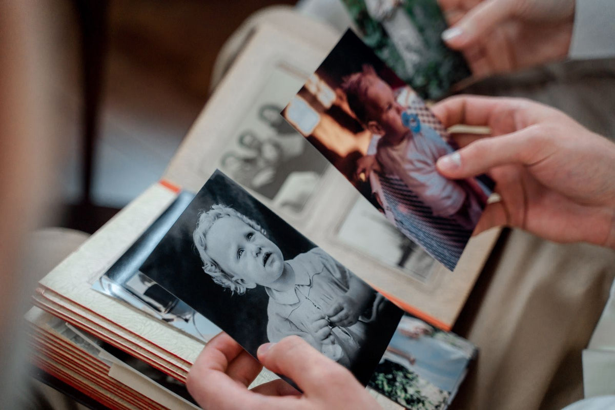 Hands holding printed family photographs over an album
