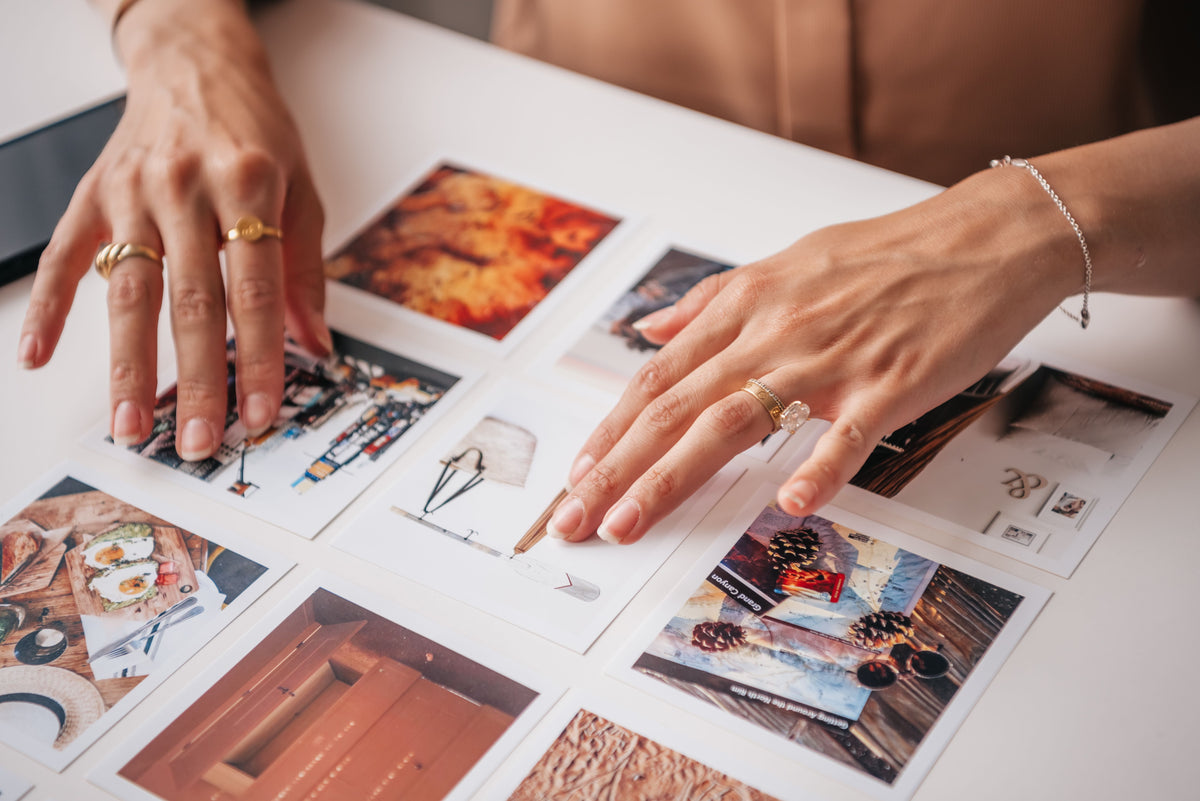 Hands arranging printed photographs while selecting an image