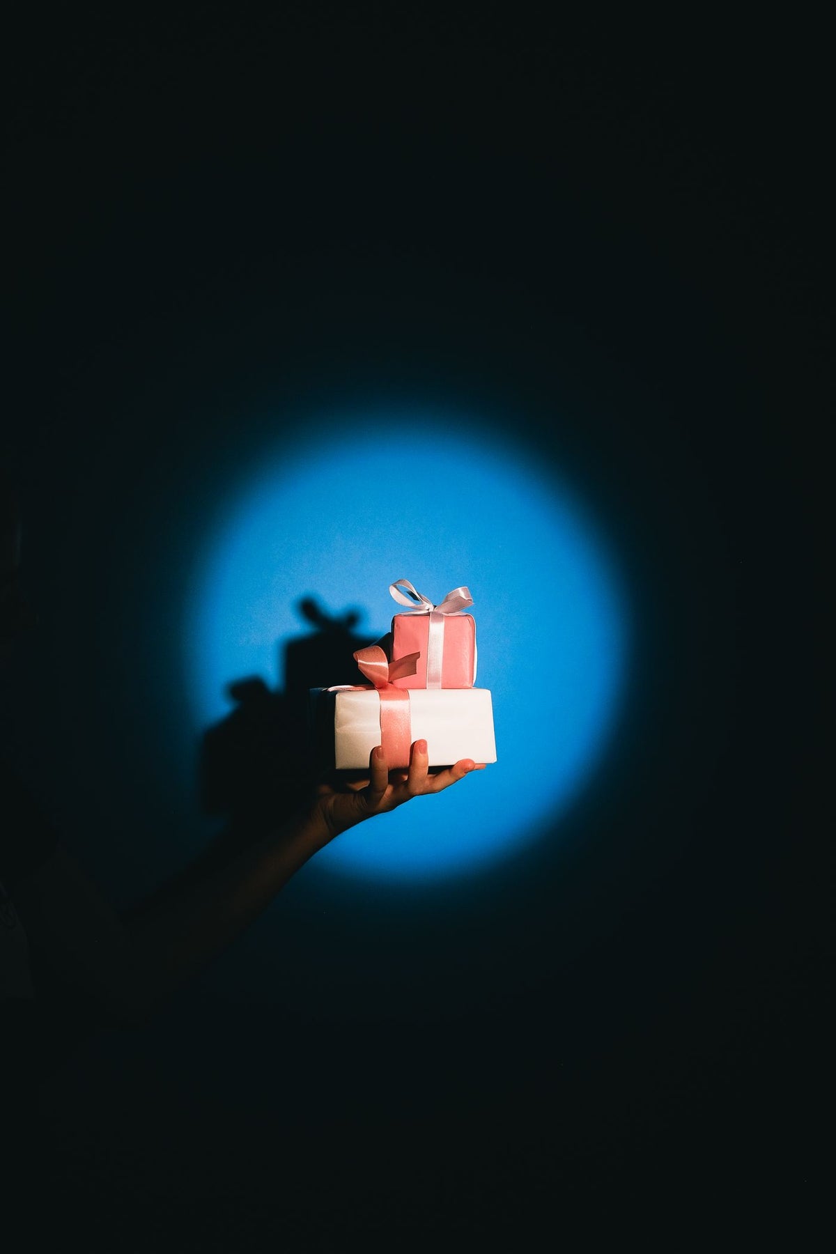 A hand presenting wrapped gifts under a blue spotlight